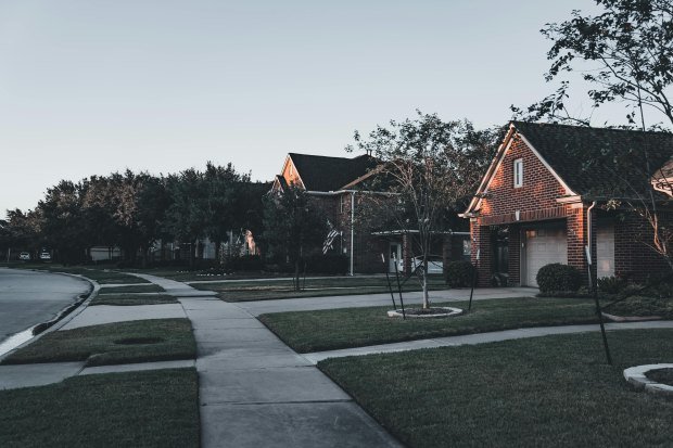 A serene suburban scene featuring brick houses and landscaped lawns at dusk.