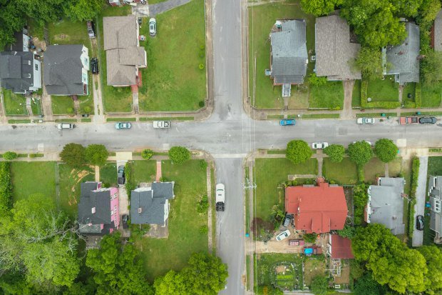 Aerial photo capturing an intersection in a suburban neighborhood with houses and greenery.