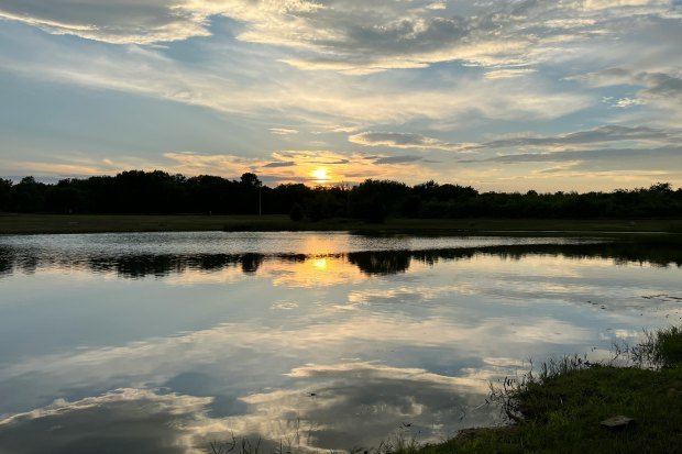 Peaceful sunset reflecting on a serene lake creating a calm and picturesque scene.